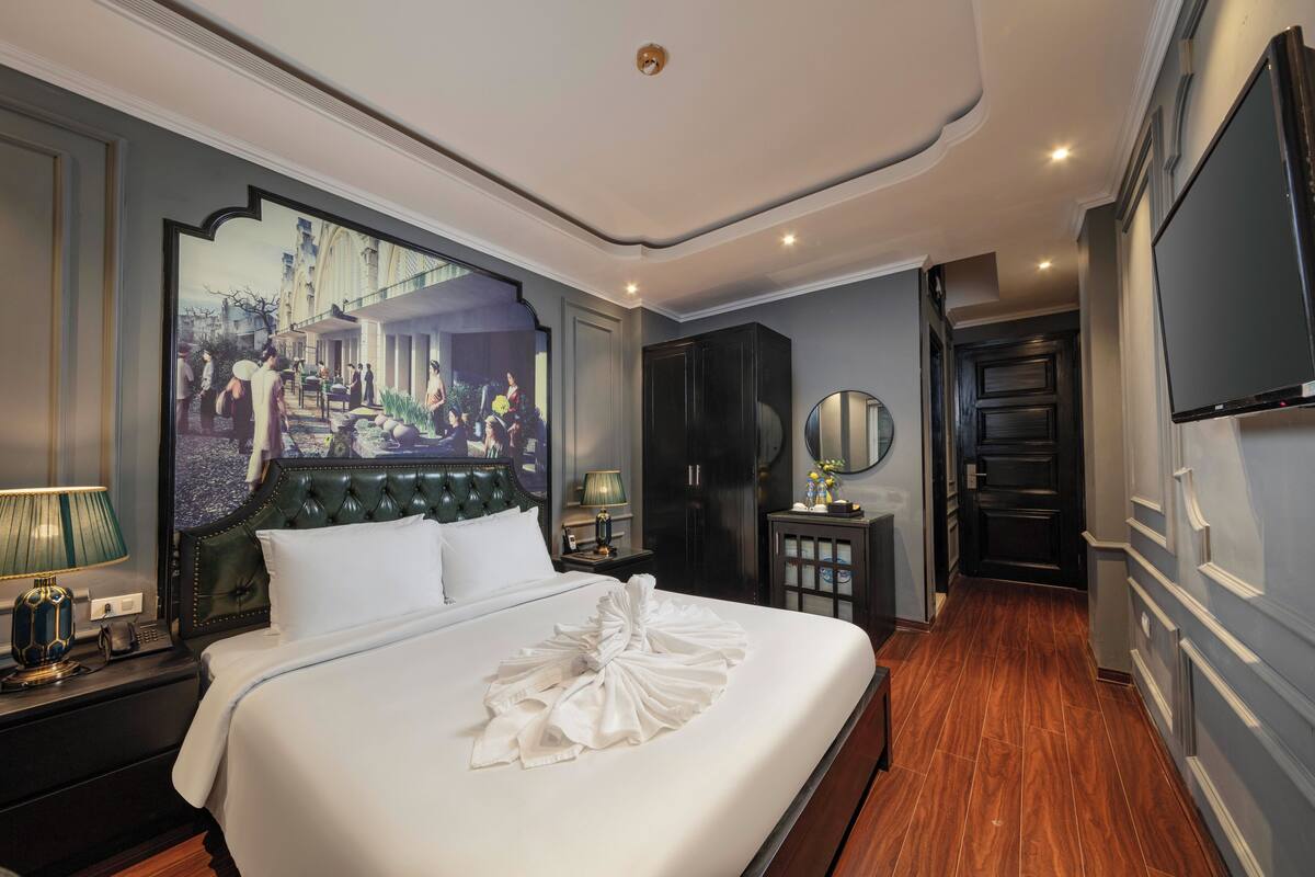 A hotel room with a large bed, a flat-screen TV, a wardrobe, and a mirror.