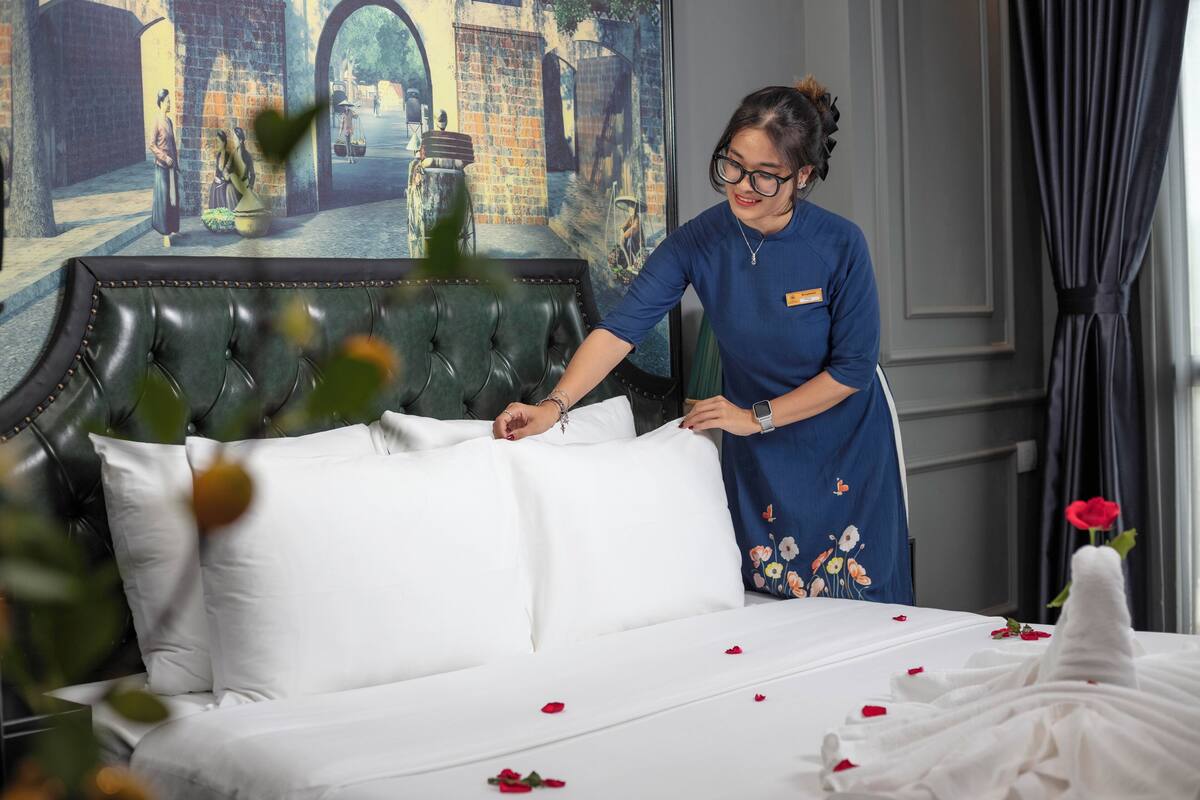 A hotel room with a large bed, a decorative headboard, and a mural on the wall depicting a street scene.