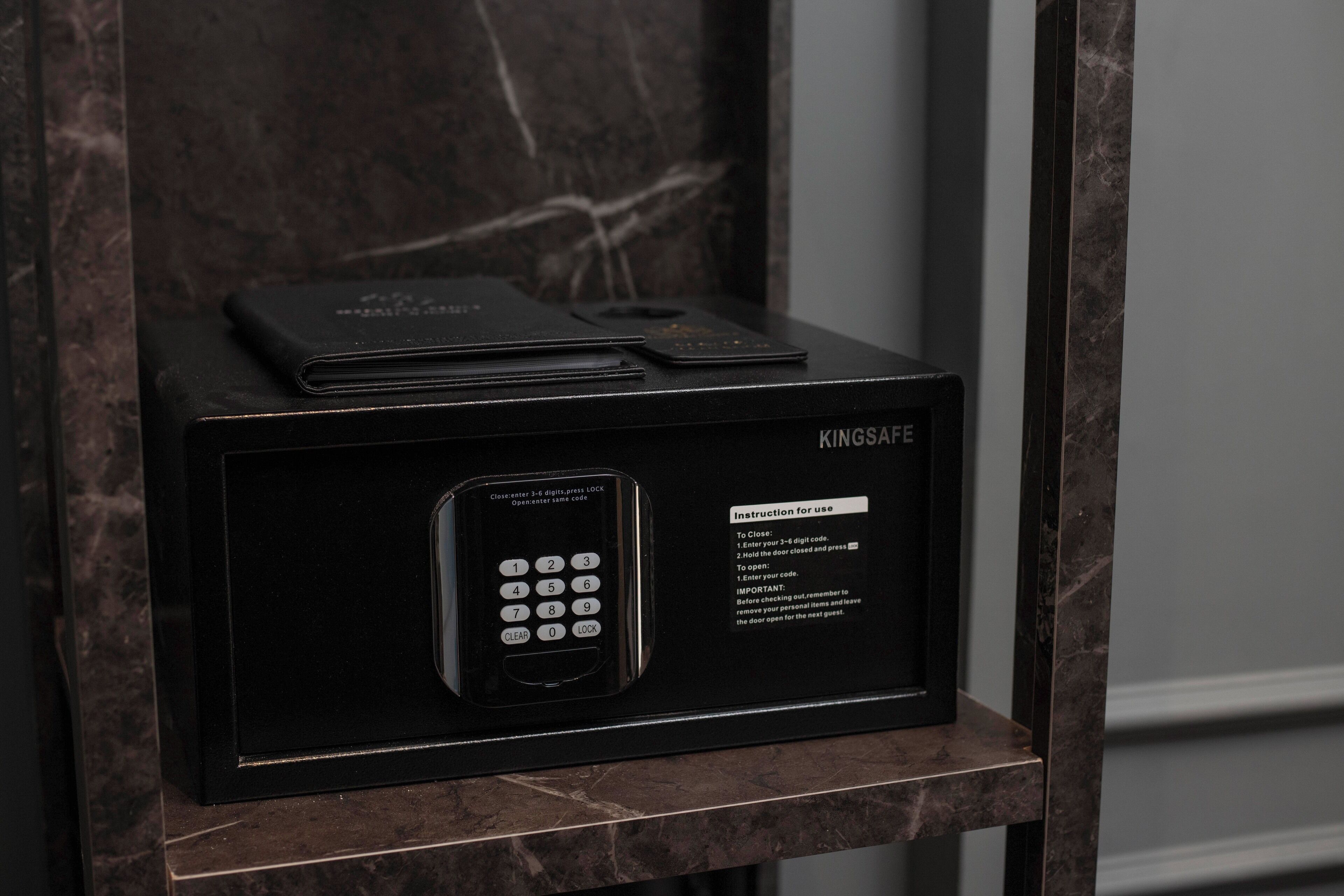A black safe with a keypad and instructions for use, placed on a marble surface.
