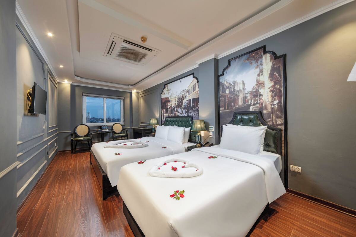 A hotel room with two beds, a large window, a television, and a decorative wall painting.