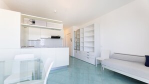 A modern, minimalist living space with a kitchen, dining area, and a large shelving unit. - BILOCALE ACQUAMARINA - BILOCALE ACQUAMARINA (Marciana Marina)
