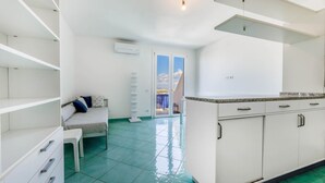 A modern kitchen with white cabinets and a green tiled floor. - BILOCALE ACQUAMARINA - BILOCALE ACQUAMARINA (Marciana Marina)