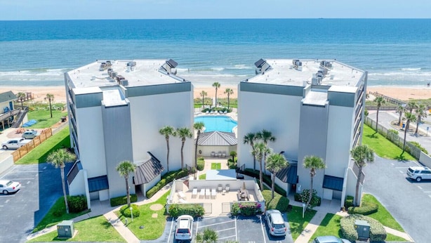 Ein modernes Hotel mit zwei symmetrischen Gebäuden, einem Pool und Blick auf den Strand.