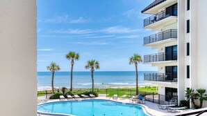Ein Hotel mit Pool, Palmen und Meerblick.