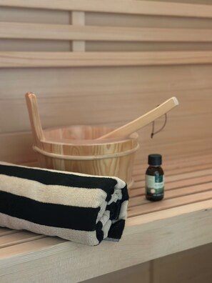 A wooden shelf with a folded towel, a wooden bowl with a spoon, and a small bottle. - Nature Views & Sauna in the Eifel (Unknown)
