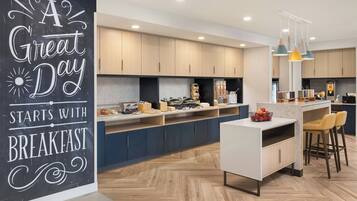 Una cocina moderna con armarios de madera, una isla central con taburetes altos y un letrero de pizarra en la pared.