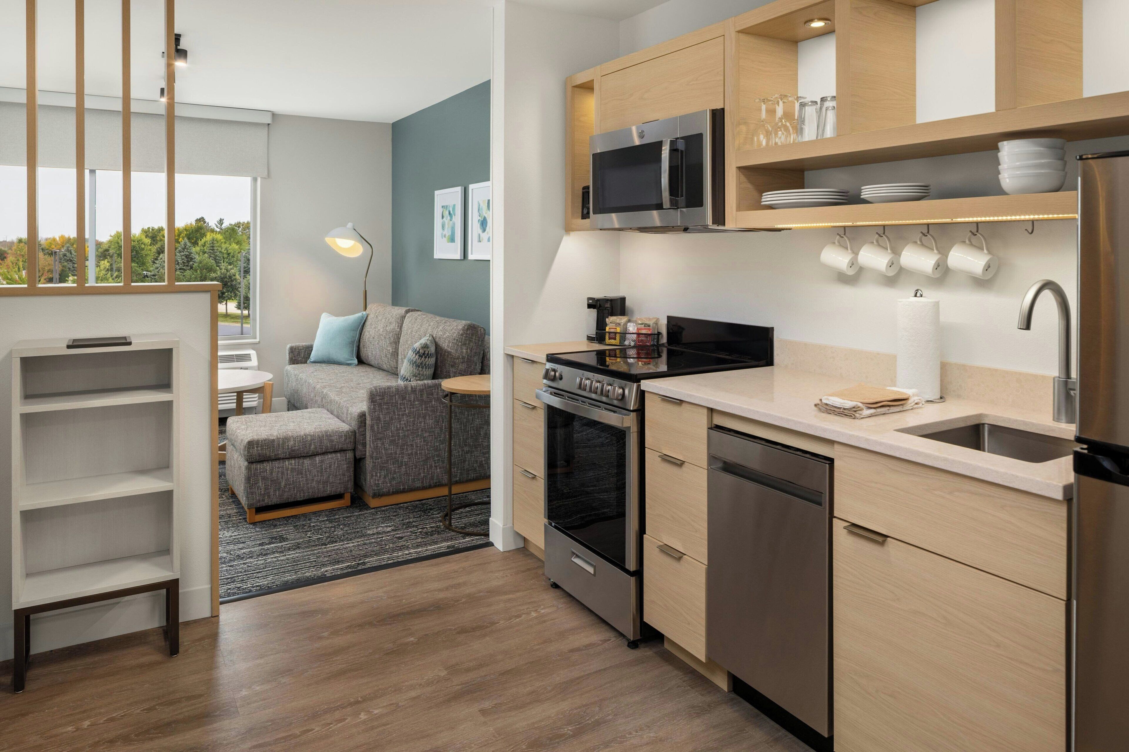 Une cuisine moderne dotée d’appareils électroménagers en acier inoxydable, de meubles en bois et d’un four encastré.
