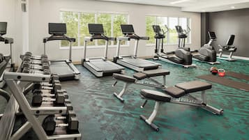 A gym with treadmills, dumbbells, and weight benches.