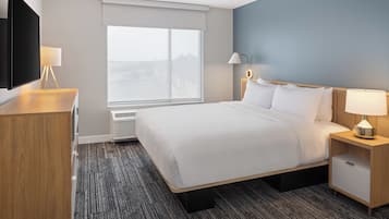 A hotel room with a bed, a desk, a TV, and a window with a view.