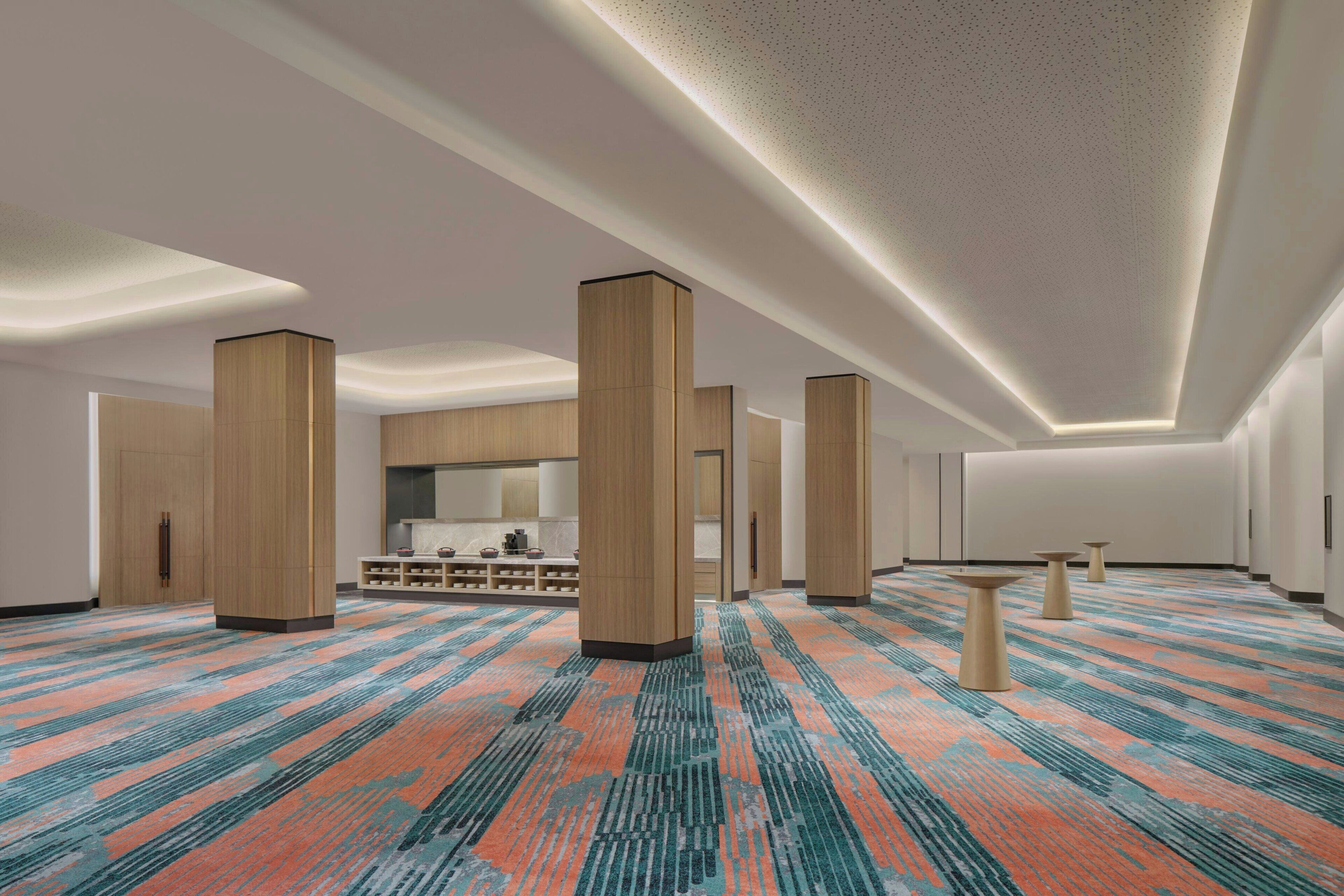 A spacious hotel lobby with high ceilings, large wooden pillars, and a patterned carpet.