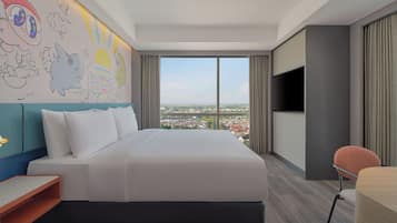 Une chambre d’hôtel avec un grand lit, une télévision, un bureau et une vue sur la ville.