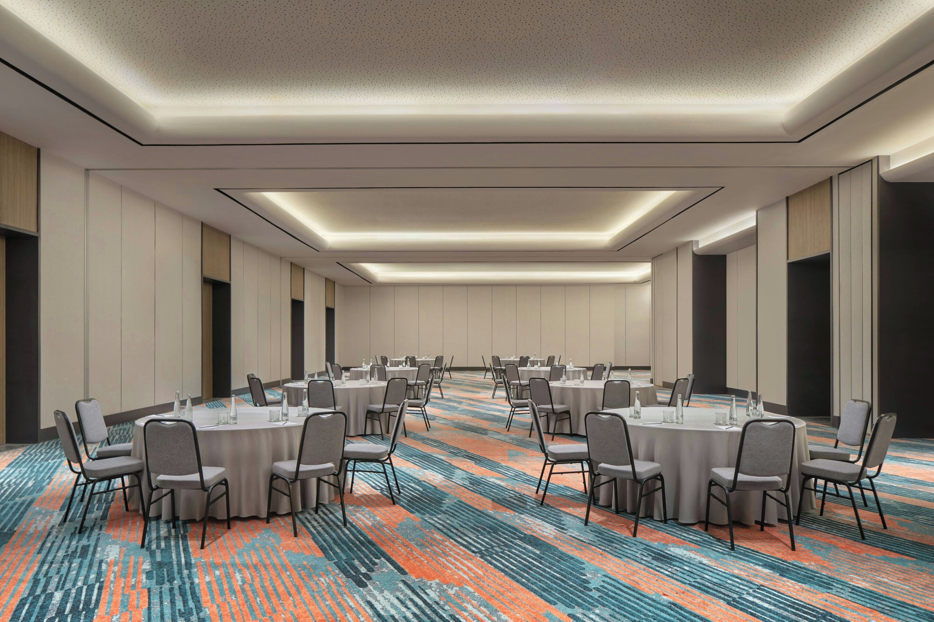 A conference room with round tables and chairs, a patterned carpet, and a modern ceiling design.
