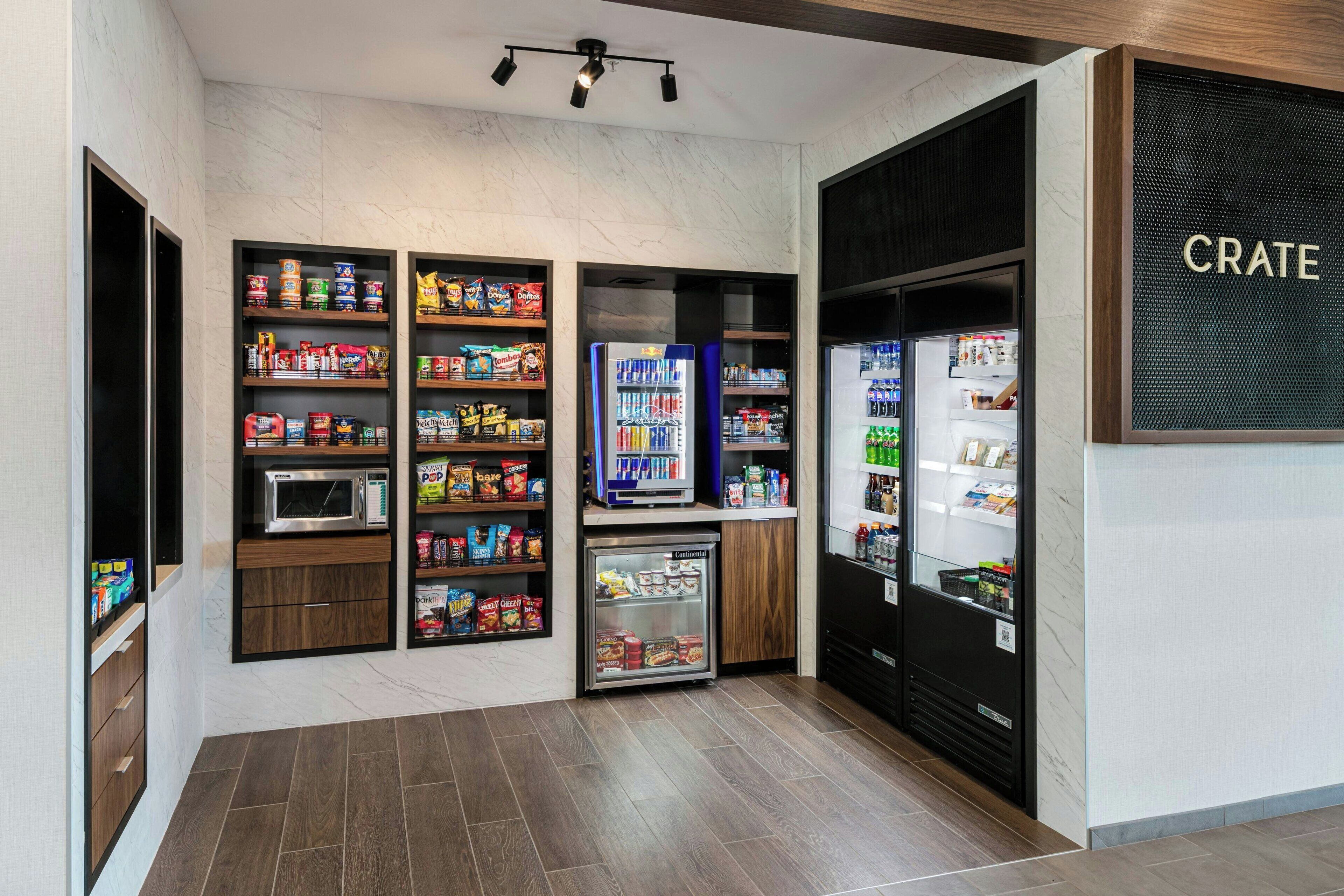 A snack bar with shelves stocked with various snacks and beverages, a microwave, and a refrigerator.