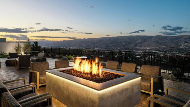 A fire pit surrounded by wicker chairs on an outdoor deck with a view of distant mountains. - Courtyard by Marriott Lewiston (Lewiston)