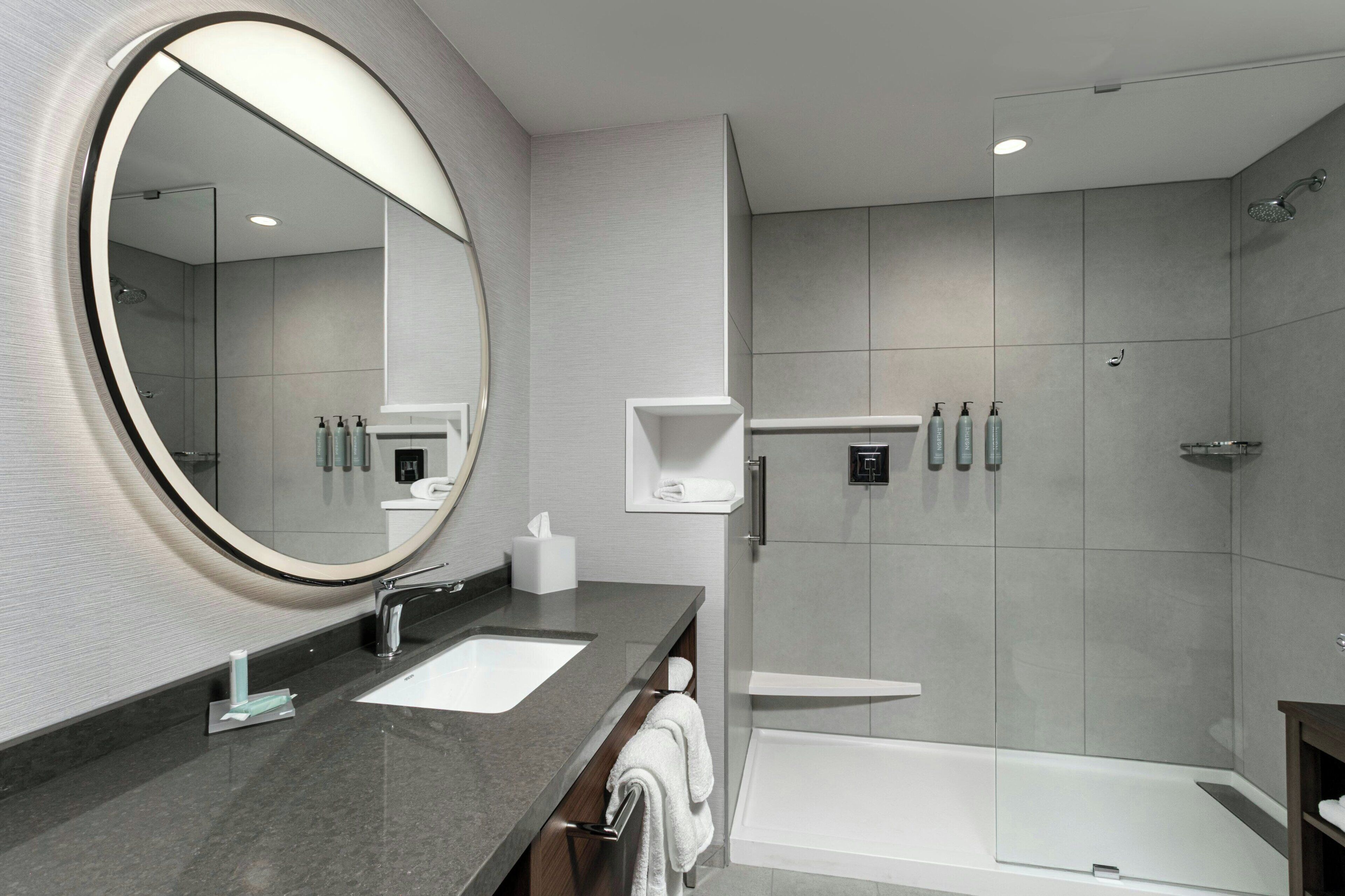 Un baño moderno con un espejo grande, dos lavamanos, una ducha y una bañera.