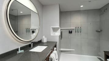 Un baño moderno con un espejo grande, dos lavamanos, una ducha y una bañera.