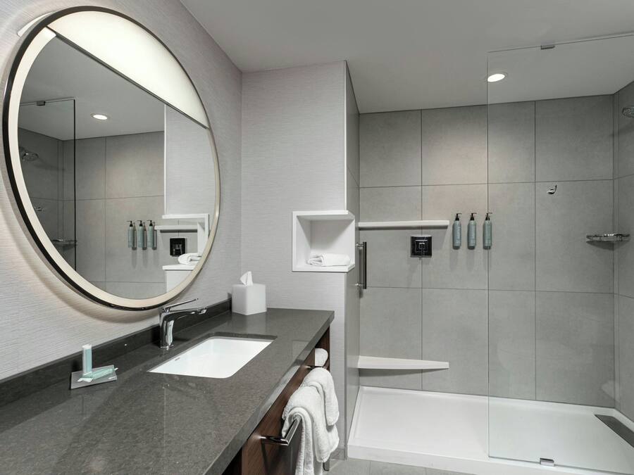 Un baño moderno con un espejo grande, dos lavamanos, una ducha y una bañera.