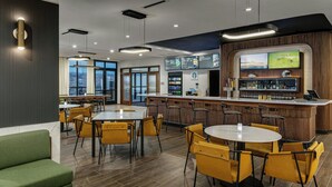 A modern bar area with a wooden bar counter, yellow chairs, and a large TV screen. - Courtyard by Marriott Lewiston (Lewiston)