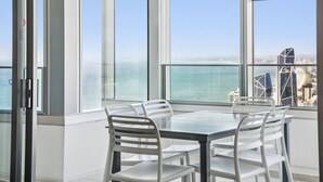 A modern room with a glass table and chairs, large windows with a city and water view. - Sky Home on 54th Floor - Stunning South East Views (Surfers Paradise)