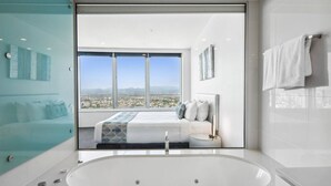 A modern bedroom with a large window, a bed, and a bathroom with a bathtub. - Sky Home on 54th Floor - Stunning South East Views (Surfers Paradise)