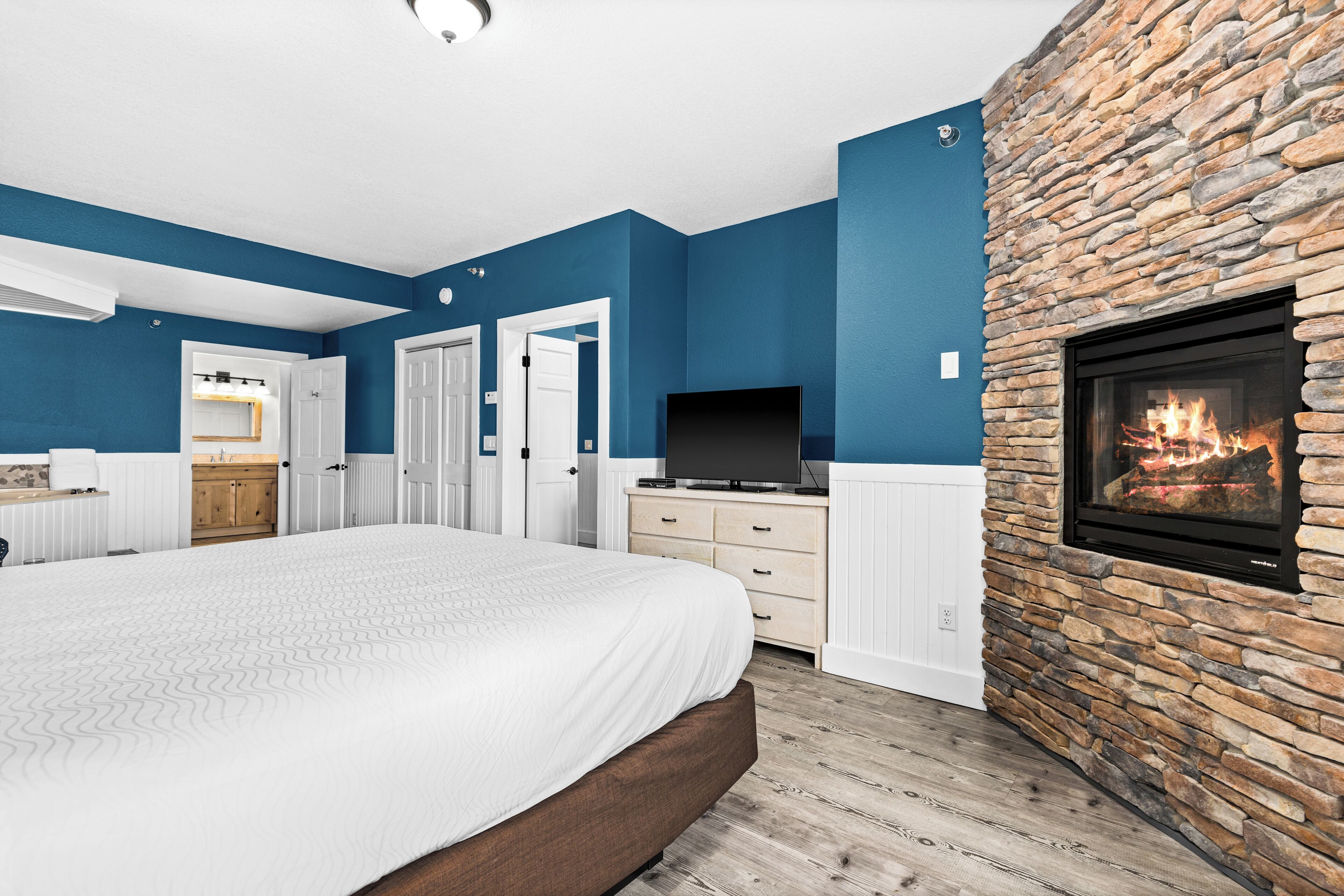 Un dormitorio con una cama grande, una chimenea de piedra y una televisión.