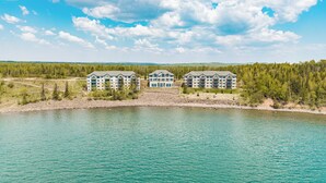 Un complejo turístico con varias construcciones a orillas de un lago, rodeado de bosque.