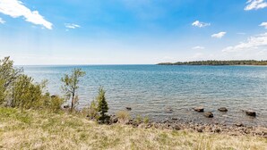 Una vista despejada de un lago con orilla rocosa y vegetación escasa.
