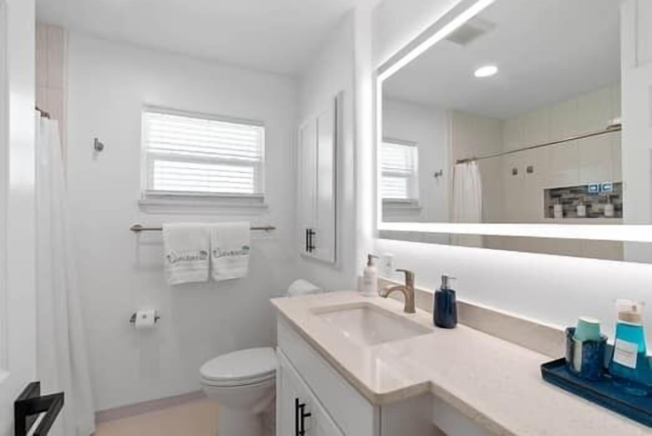 Un baño moderno con inodoro, lavamanos y espejo.