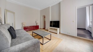 Ett modernt vardagsrum med en grå soffa, ett rött skåp, en platt-TV och ett litet soffbord.