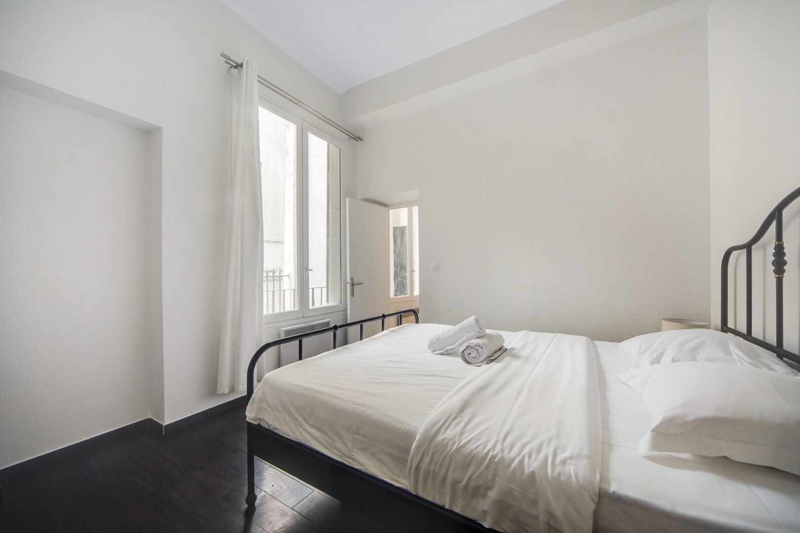 A bedroom with a bed, a window with curtains, and a radiator.