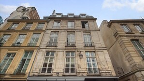 En byggnad med flera våningar i en klassisk arkitektonisk stil, med stora fönster och balkonger.