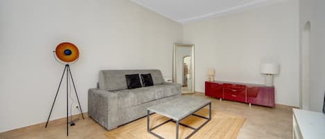 A modern living room with a grey sofa, a small table, a red cabinet, and a floor lamp.