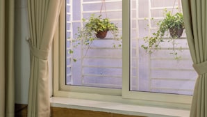 A room with a large window, curtains, and a bed.