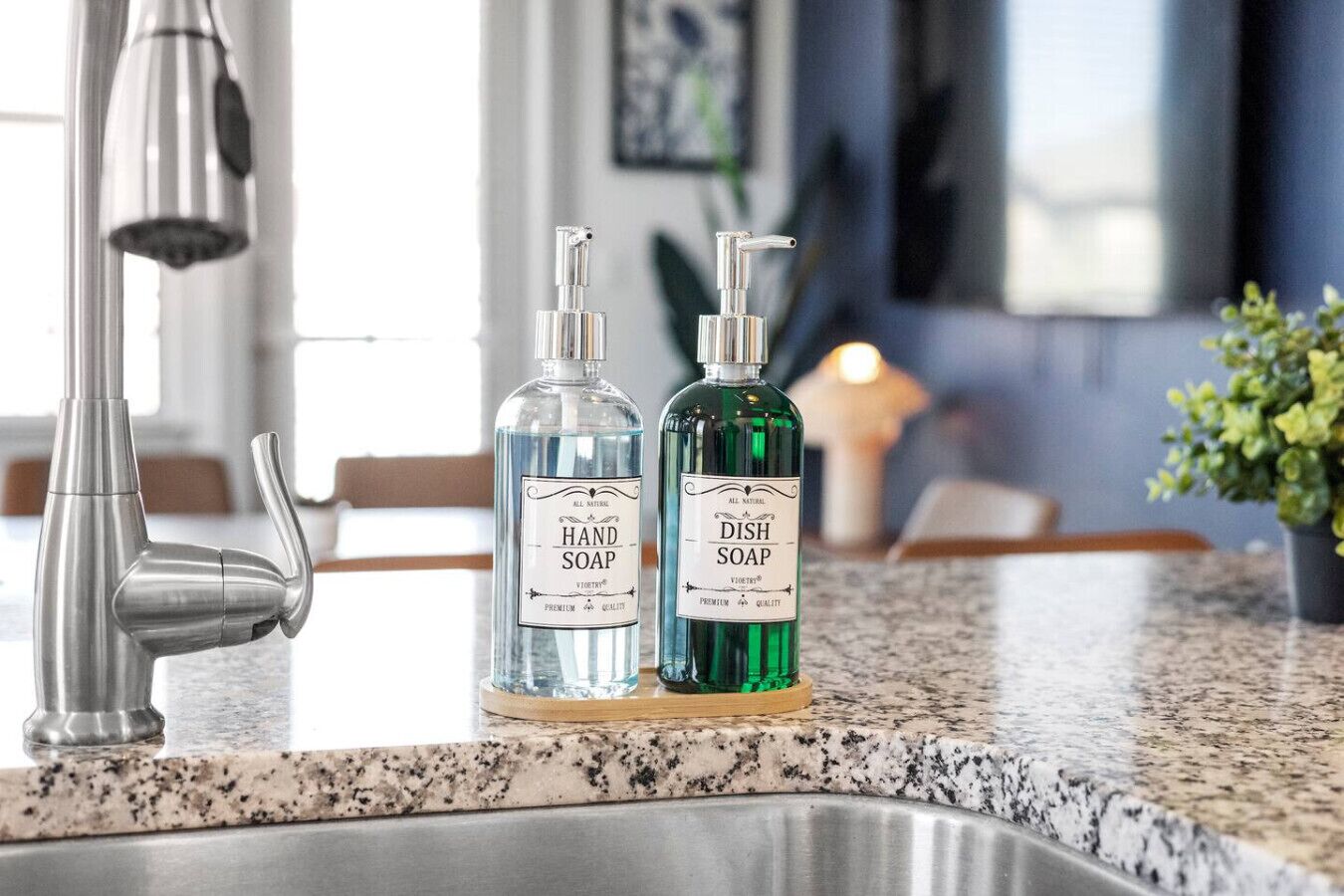 A kitchen with a stainless steel faucet, two bottles of soap labeled 'HAND SOAP' and 'DISH SOAP' on a granite countertop.