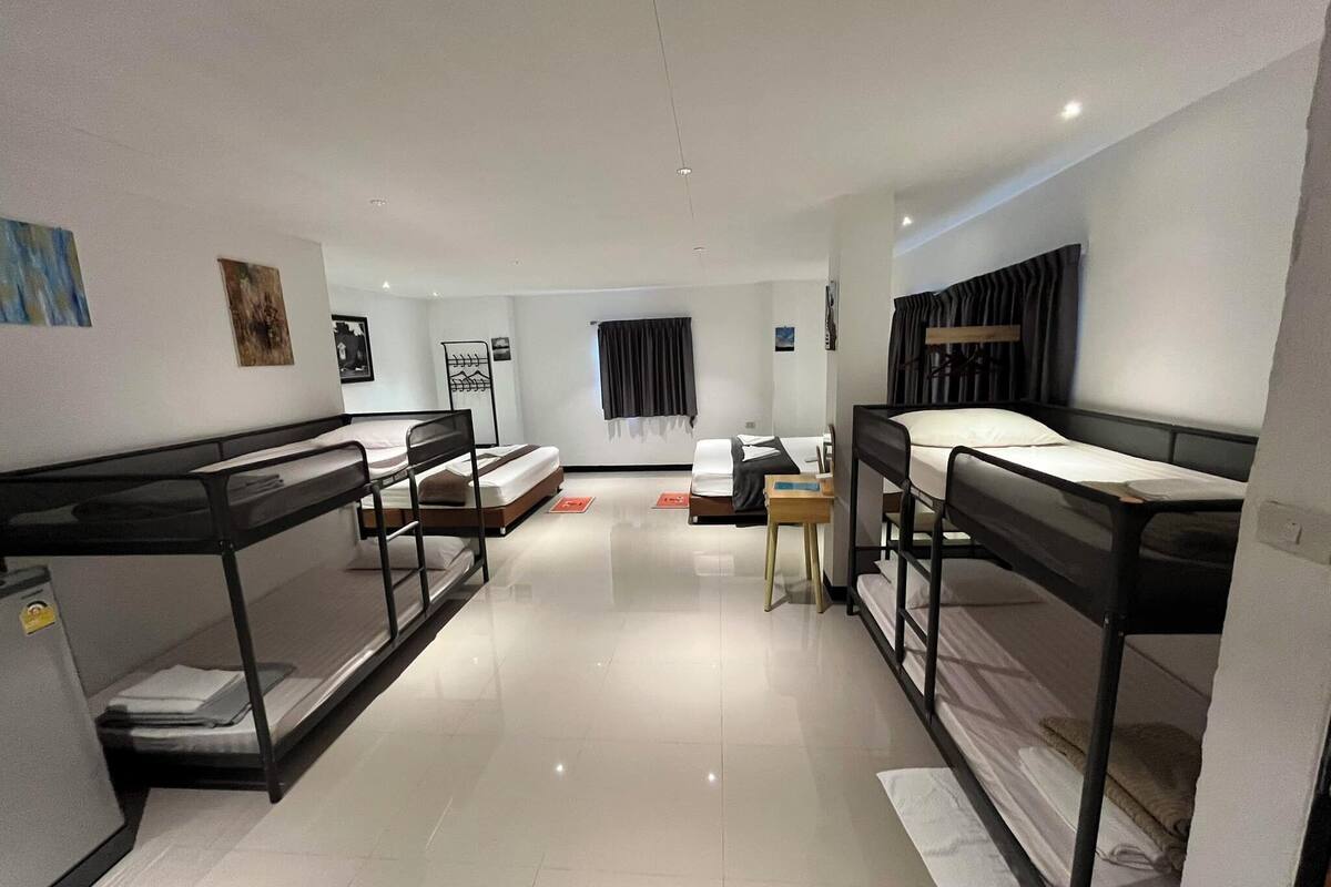 A modern hotel room with bunk beds, a small desk, and a window with curtains.