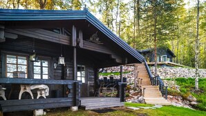 A log cabin with a porch, outdoor seating, and a staircase leading to a second building. - Stay North - Parmaranta (Ylöjärvi)