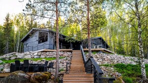 A cabin with a wooden staircase leading to a deck, surrounded by a forest. - Stay North - Parmaranta (Ylöjärvi)