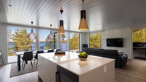 A modern kitchen with a large island, dining area, and a view of the outdoors. - Stay North - Parmaranta (Ylöjärvi)