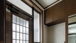 A hotel entrance with a frosted glass door, a wooden floor, and a small plant on the wall. - KOTONOHA (Otaru)