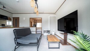 A modern living room with a sofa, a coffee table, a TV, and a plant. - KOTONOHA (Otaru)