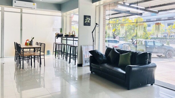 Un intérieur moderne avec un canapé en cuir noir, un coin repas avec des chaises et une grande fenêtre donnant sur la rue.