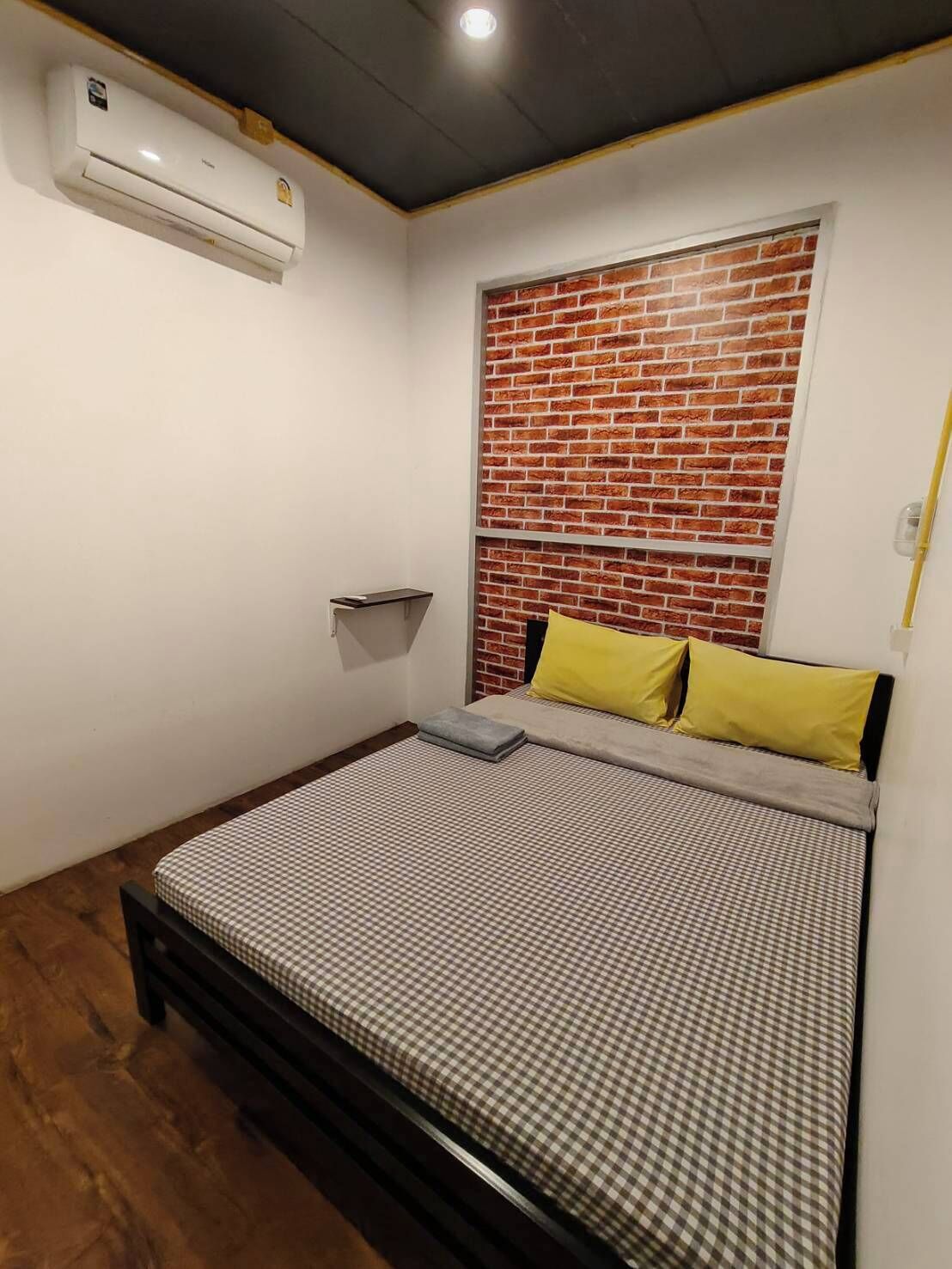 A bedroom with a bed, a brick-patterned wall, and an air conditioning unit.