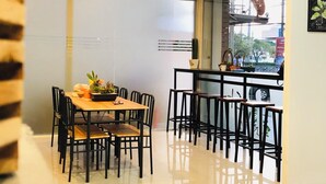 Un espace repas moderne avec une longue table et de nombreuses chaises, un appareil de climatisation au-dessus et une vue par la fenêtre.