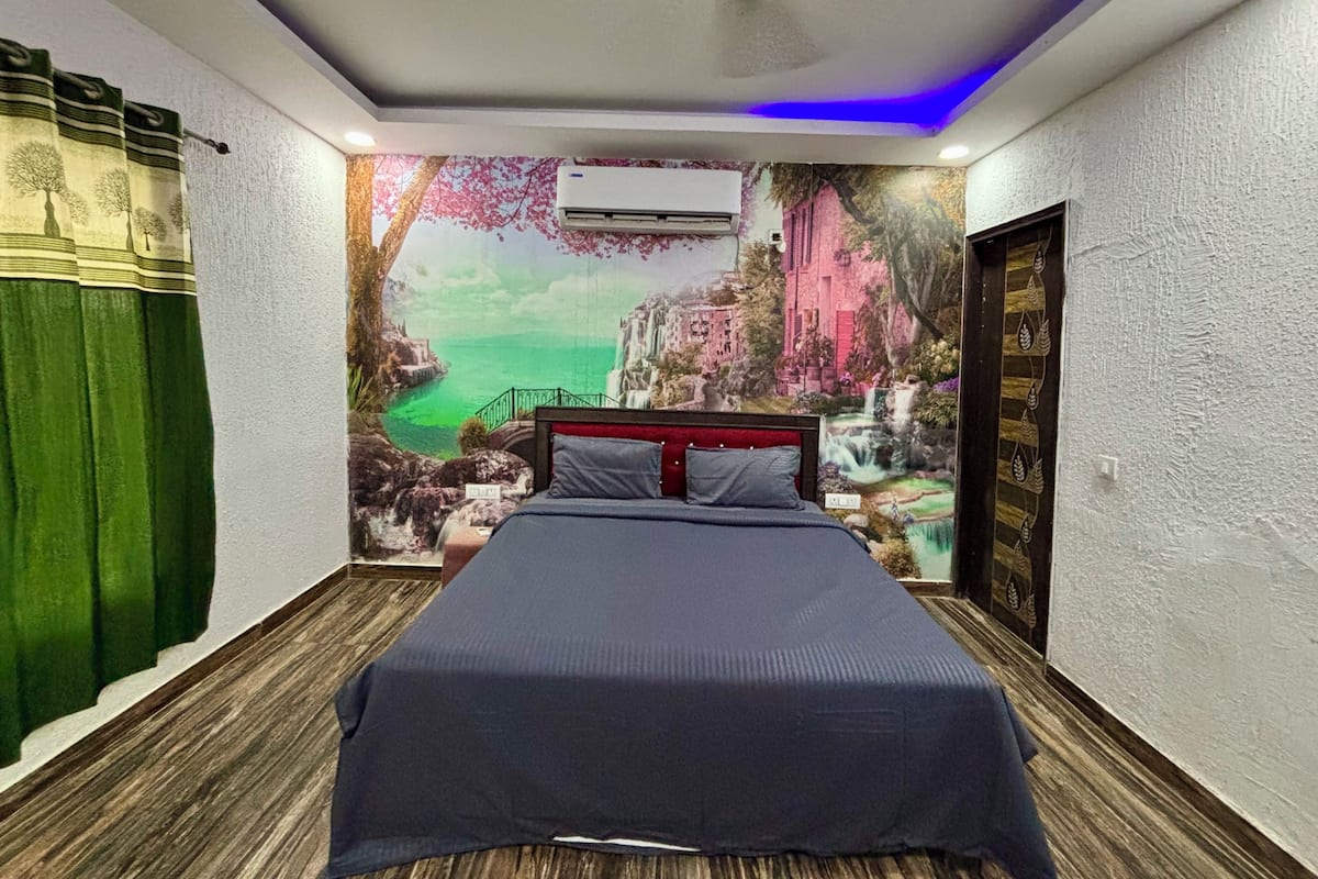 A bedroom with a bed, a mural, an air conditioner, and a door.