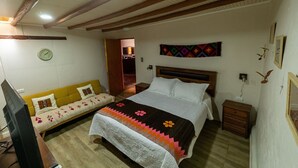 Une chambre à coucher avec un lit, un canapé, une télévision et un plafond en bois.