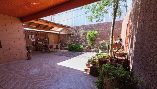 Un patio couvert doté d’un sol carrelé, de plantes en pot et de mobilier d’extérieur.