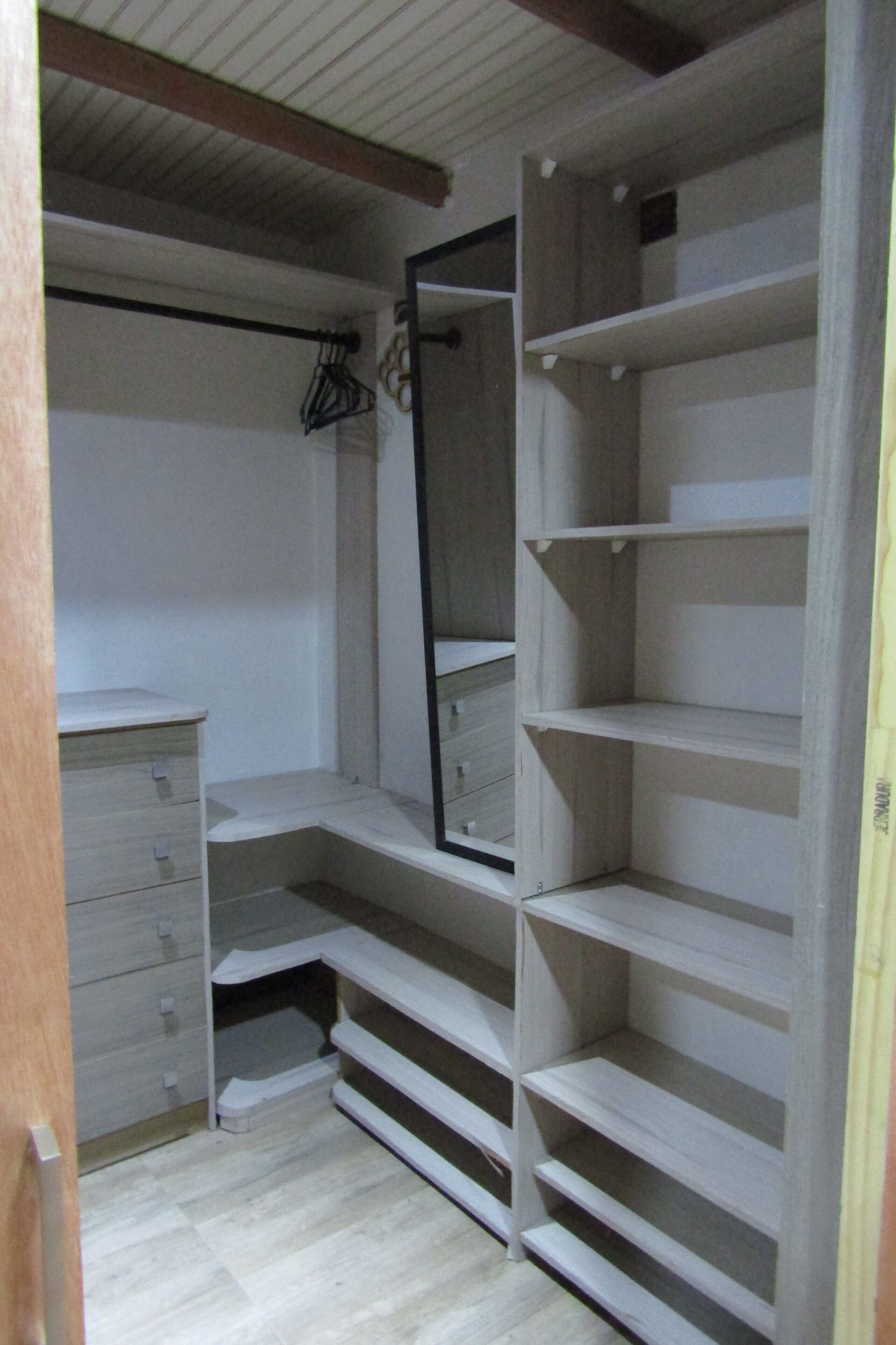 Un vestidor amplio con estantes abiertos, un espejo y un aparador de madera.
