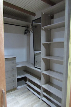 Un vestidor amplio con estantes abiertos, un espejo y un aparador de madera.
