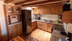 Une cuisine équipée de meubles en bois, d’un réfrigérateur, d’un four à micro-ondes, d’une cuisinière et d’un évier.