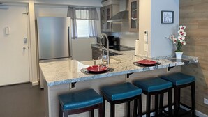 A modern kitchen with a central island, stainless steel appliances, and bar stools. - Dazzling Waikiki Apt Sleeps 7-excellent A/C & PARKING included (Honolulu)